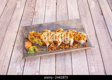 Sushi uramaki crunchy salmon roll with sauce, avocado, spicy wasabi and ginger with onion Stock Photo