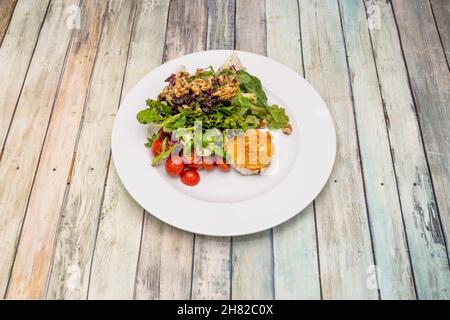 Lettuce salad with cherry tomatoes, California walnuts and raisins with fried goat cheese Stock Photo