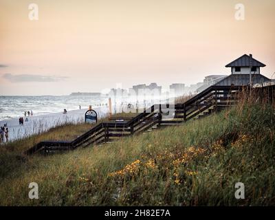 Grass covered sand dunes leading down to the beach on a windy day with high surf on Miramar Beach looking toward high rise condos Destin Florida, USA. Stock Photo