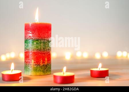 Christmas candles and tealights on wooden table with defocused holiday lights in background Stock Photo