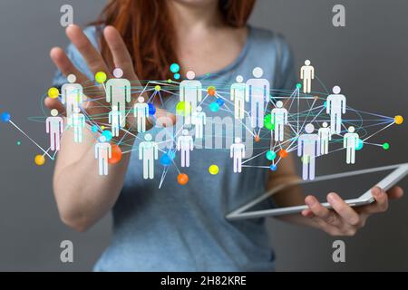Hologram of a network of people working as a team, projecting from a woman's tablet Stock Photo