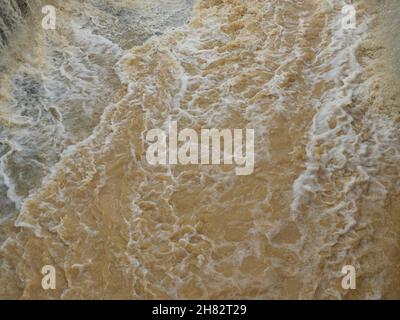 The brown water was flowing fast and was splashing violently, Flood in rainy season, Thailand Stock Photo