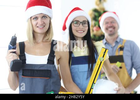 Team of builders with working tool against background of New Year tree Stock Photo