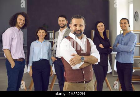 Confident caucasian businessman standing with folded arms smiling at camera Stock Photo