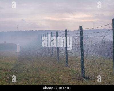 Rows of barbed wire on the state border. The separation of the two countries. Foggy autumn landscape  Stock Photo