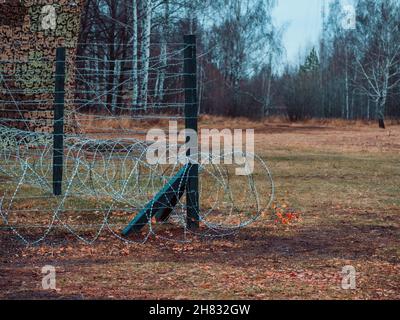 Rows of barbed wire on the state border. The separation of the two countries. Foggy autumn landscape  Stock Photo