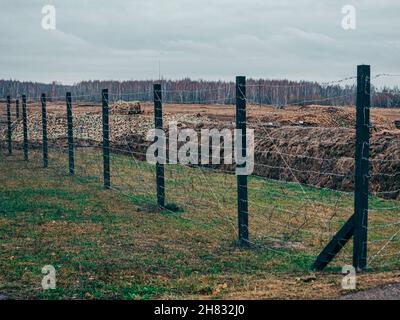 Rows of barbed wire on the state border. The separation of the two countries. Foggy autumn landscape  Stock Photo