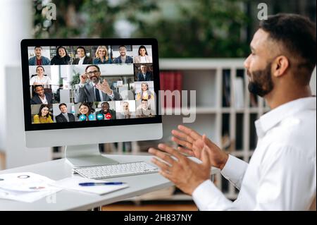 Online video meeting, distant communication. Indian businessman, holds negotiation with multiracial group of successful business partners, virtual business meeting, telecommunication concept Stock Photo