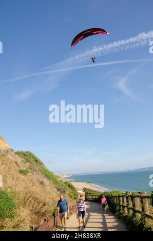 Paraglider above cliffs and beach huts at Barton on Sea, Hampshire, England, UK Stock Photo