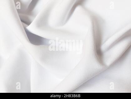 White crumpled or wavy fabric texture background. Abstract linen cloth soft waves. Creases of satin, silk, and cotton. Smooth elegant silk or atlas Stock Photo