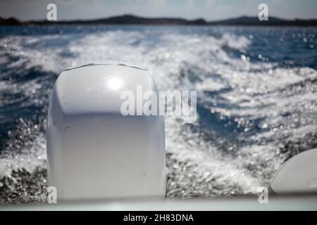 Close-up shot of motorboat engine during the drive on the beautiful blue seawater. Foam trail, boats wake, in the seawater. Stock Photo