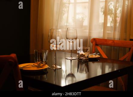 Wine glasses on black table near window with thin curtain Stock Photo
