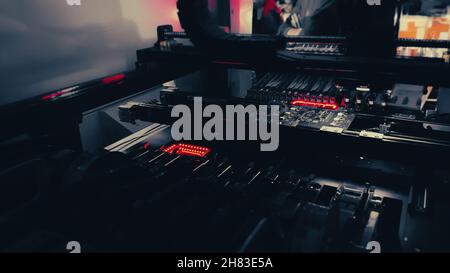 Production of high-tech computer chips on an automatic SMT machine. Digital technologies for automation of industry. Red neon lights illuminate Chip Components for automation test. Stock Photo