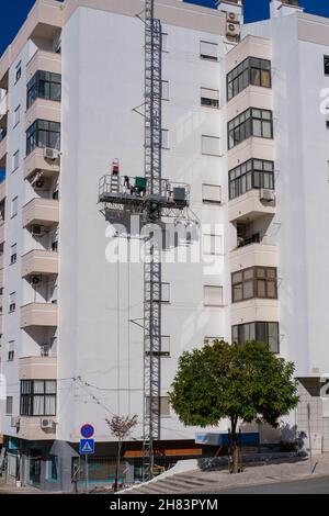 Castelo Branco, Portugal - November 09 2021: Mask climbing aerial access platform being used on high rise building facade Stock Photo
