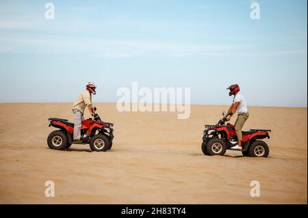 Two racers in helmets stand face to face on atvs Stock Photo