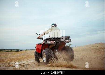 An atv rider racing in desert, downhill riding in desert sands, action ...