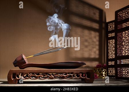 Smoke from burning incense sticks standing on lotus incense holder Stock Photo