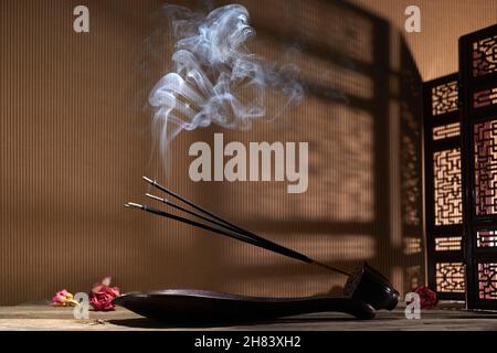 Smoke from burning incense sticks standing on lotus incense holder Stock Photo