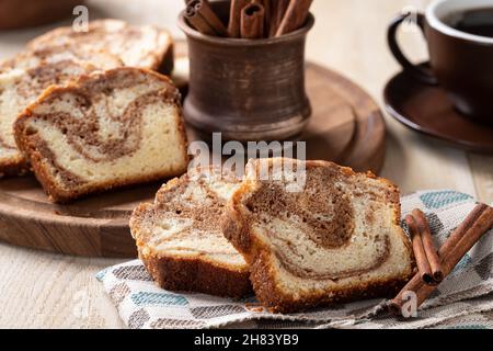 Slices of cinnamon swirl cake and cinnamon sticks on a wooden table Stock Photo