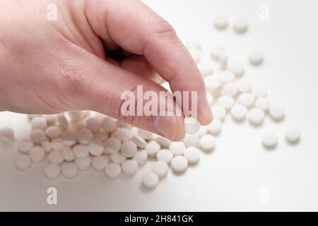 One white round pill in a hand. Vitamin pills. Stock Photo