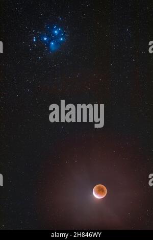 The partial eclipse of the Moon of November 19, 2021, with the Moon below the Pleiades star cluster, M45, in Taurus, the hallmark feature of this ecli Stock Photo