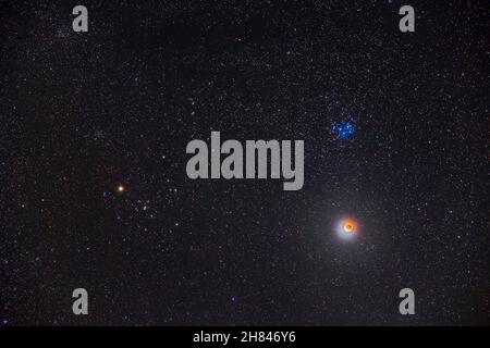 The partial eclipse of the Moon of November 19, 2021, with the Moon below the Pleiades star cluster, M45, and near the Hyades cluster and Aldebaran at Stock Photo