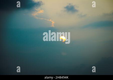 Sunset on a hazy summer day with the sun partially hidden behind clouds - blue hour in the evening Stock Photo