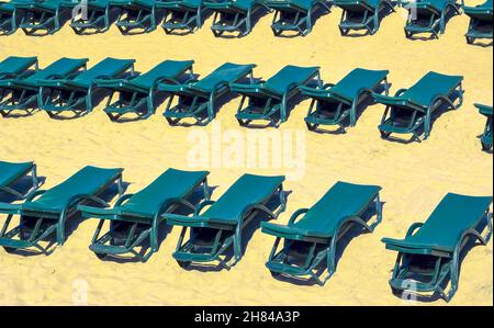 Rows of free green sun loungers on an empty sandy beach. Closed Vacation Concept or low season Stock Photo