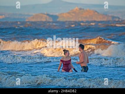 Portobello, Edinburgh, Scotland, UK. 27th November 2021. Temperature of 2 degrees and large waves from the remnants of Storm Arwen did not stop Edinburgh University students Elly and Fraser from having an exceptionally chilly afternoon dip in the Firth of Forth. Credit: Arch White Stock Photo