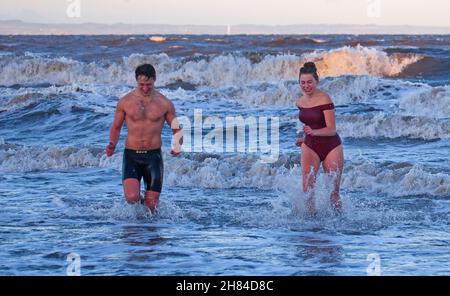 Portobello, Edinburgh, Scotland, UK. 27th November 2021. Temperature of 2 degrees and large waves from the remnants of Storm Arwen did not stop Edinburgh University students Elly and Fraser from having an exceptionally chilly afternoon dip in the Firth of Forth. Credit: Arch White Stock Photo