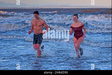 Portobello, Edinburgh, Scotland, UK. 27th November 2021. Temperature of 2 degrees and large waves from the remnants of Storm Arwen did not stop Edinburgh University students Elly and Fraser from having an exceptionally chilly afternoon dip in the Firth of Forth. Credit: Arch White Stock Photo