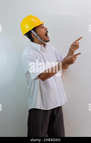 Worker with helmet isolated on white background. Black man surprise pointing. Stock Photo