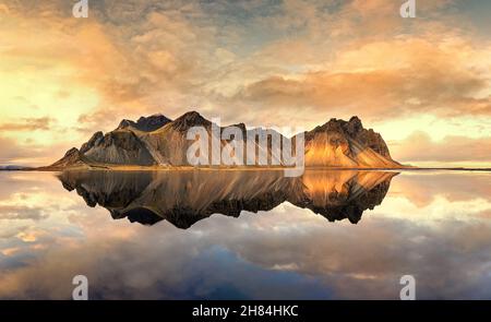 A panorama of sunset at Vestrahorn, Stokksnes peninsula. Golden hour shot with mirror reflection at dusk. South-east Iceland in autimn. Stock Photo