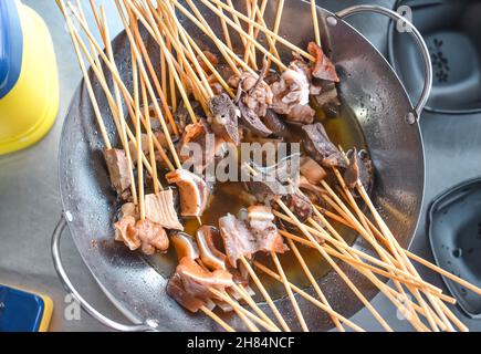Boiled pork variety meats on bamboo sticks. Famous Myanmar street food Stock Photo
