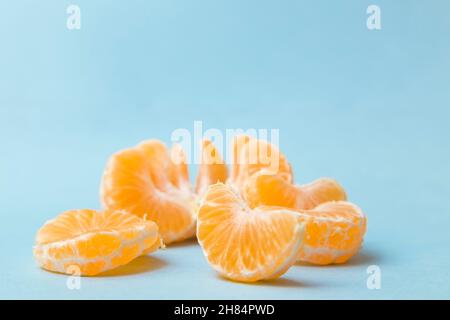 a peeled tangerine, presented in wedges and placed on a blue background Stock Photo