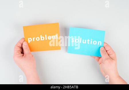 The words problem and solution are standing on orange and blue colored paper, brainstorming for new ideas, hands holding the message Stock Photo
