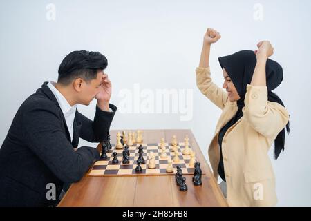 woman in veil facing man in suit while playing chess Stock Photo