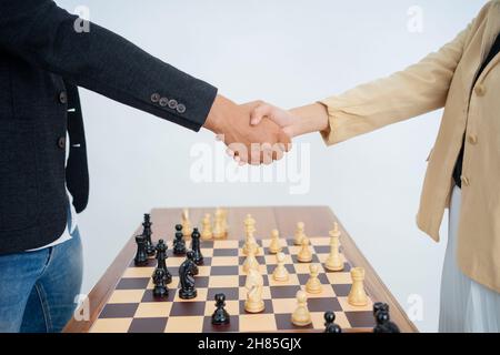 Male and female hands shaking hands over chess pieces Stock Photo