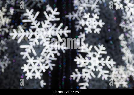 Abstract background with white bokeh lights, winter Christmas tree background with sparkling snowflakes with silhouette of people Stock Photo