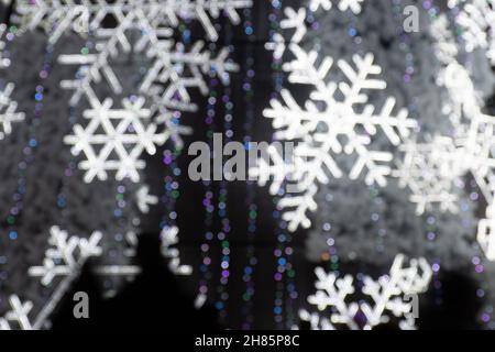 Abstract background with white bokeh lights, winter Christmas tree background with sparkling snowflakes with silhouette of people Stock Photo