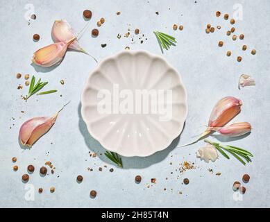 composition of decorative white plate and various spices on blue background, top view Stock Photo