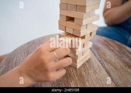 person's hand holding a block while playing tower of blocks Stock Photo