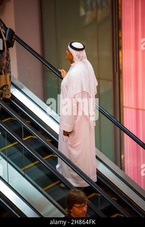 DUBAI, UNITED ARAB EMIRATES - Oct 29, 2021: A vertical shot of an arab male in thobe attire on an escalator in the Dubai Mall Stock Photo