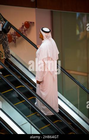 DUBAI, UNITED ARAB EMIRATES - Oct 29, 2021: A vertical shot of an arab male in thobe attire on an escalator in the Dubai Mall Stock Photo