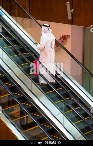 DUBAI, UNITED ARAB EMIRATES - Oct 29, 2021: A vertical shot of an arab male in thobe attire on an escalator in the Dubai Mall Stock Photo