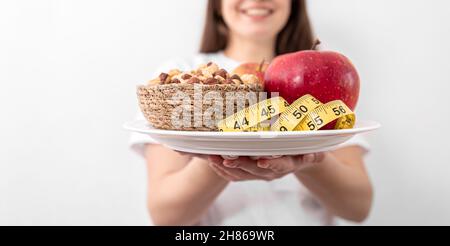 A plate with apples, nuts and a measuring tape in the hands of a young woman. Stock Photo