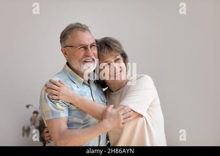 Cheerful dreamy older 60s married couple hugging with love, care Stock Photo
