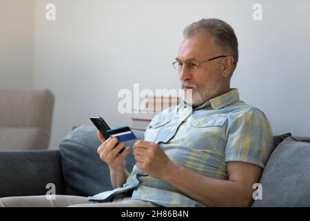 Focused senior older man using banking app, financial virtual service Stock Photo