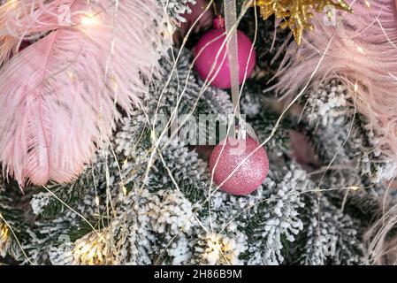 Pink Christmas ball on a fir branch. Pink details of Christmas tree. Happy New Year and Xmas concept. Stock Photo