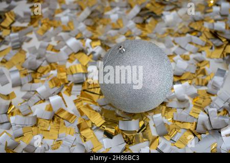 Silver shiny christmas ball on floor with golden and silver confetti. Christmas background, winter, new year concept. copy space Stock Photo